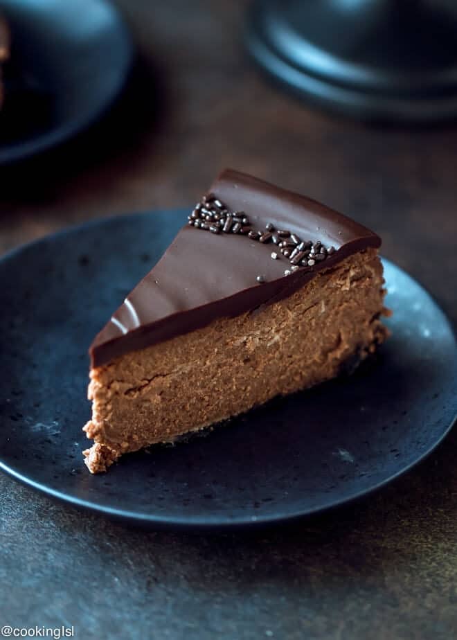 Chocolate Mascarpone Cheesecake Recipe. A slice of chocolate cheesecake topped with thick chocolate ganache. The perfect slice on a black plate.