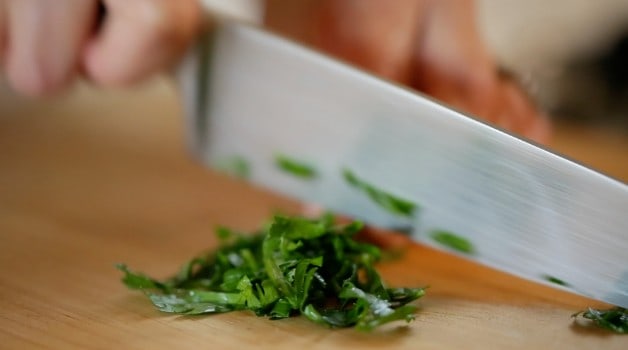 chopping flat leaf parsley on a board