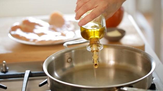 pouring olive oil into a skillet