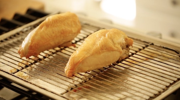 Bone-in, skin on Roasted Chicken breasts on a roasting rack in a sheet pan lined with foil