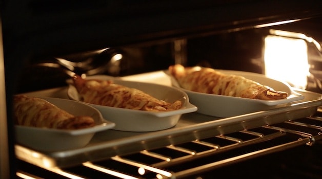 Three gratin dishes of mushrrom and chicken crepes in the oven under the broiler