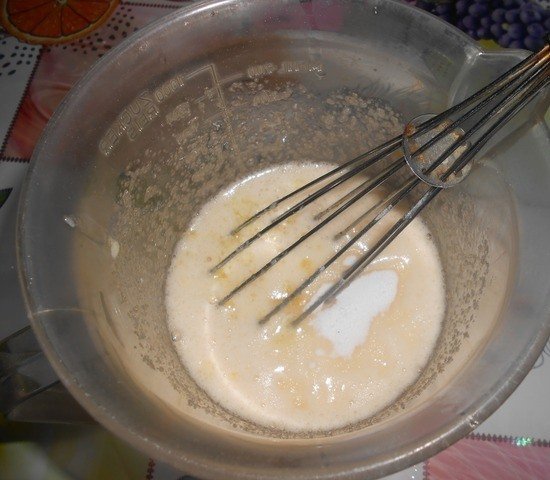 Растопленное сливочное масло и смесь из яиц и сахара в стеклянной миске с кулинарным венчиком