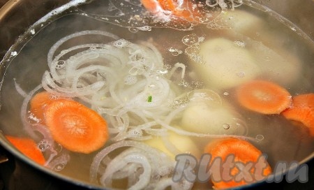 Через 1,5 часа варки бульона начинаем чистить овощи и добавлять в суп. Сначала добавляем крупно нарезанные картофель и морковь, а также репчатый лук, нарезанный тонкими кольцами.