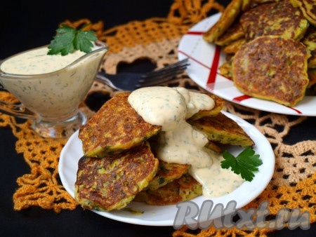 Подавать вкусные оладушки из кабачка и моркови со сметаной или сметанным соусом с зеленью.
