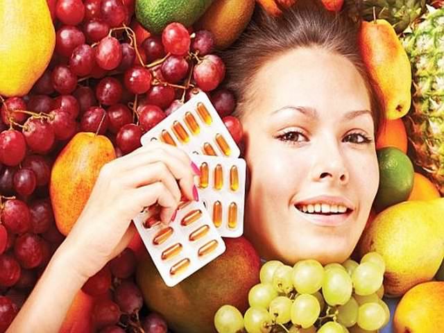 Девушка среди фруктов и с витаминами в руке
