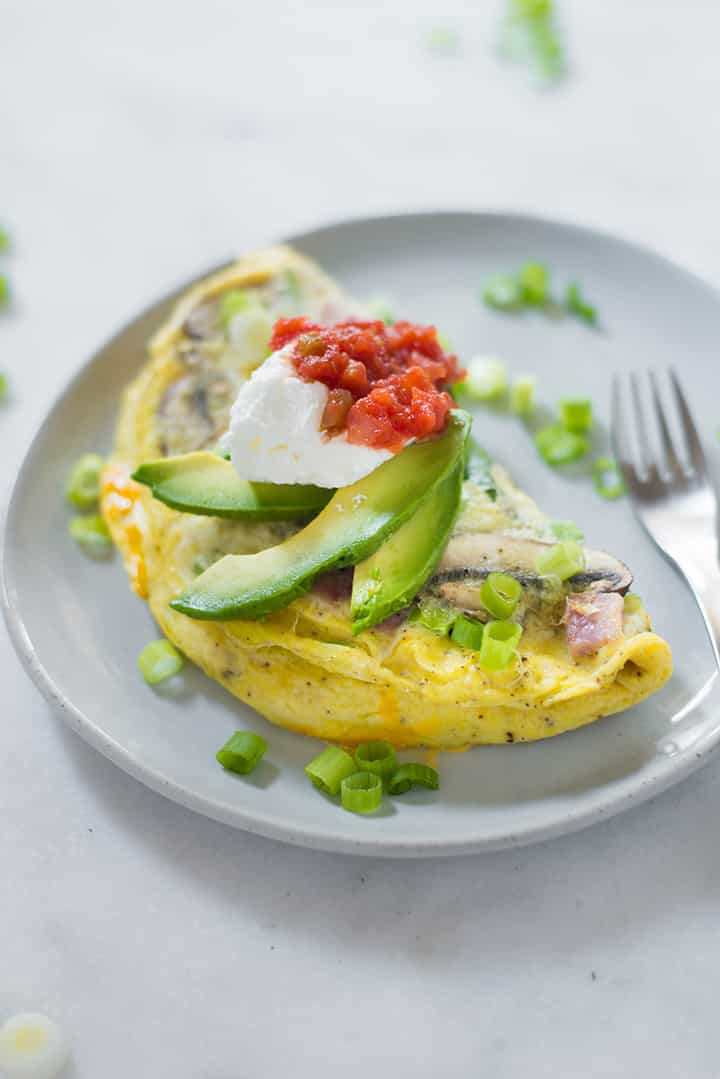 Side view of the omelet garnished with avocado slices and green onion.