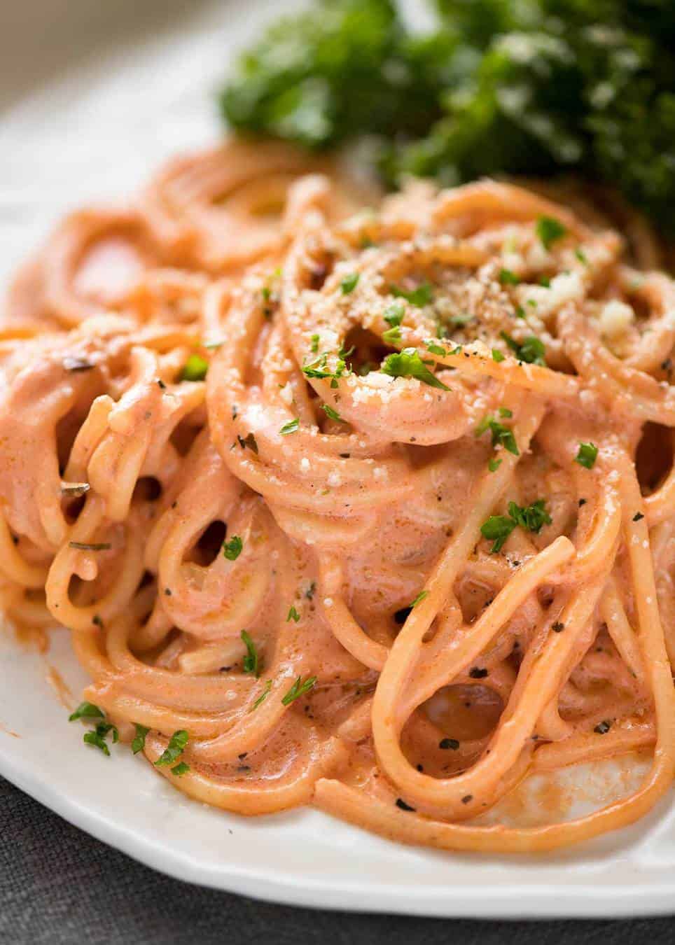 Creamy tomato pasta on a plate with marinated kale salad.